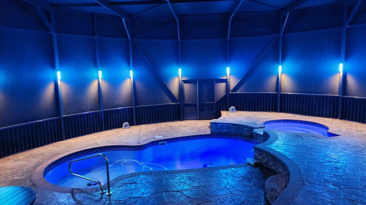 Blue LED lighting on a curved freeform pool with stamped concrete deck