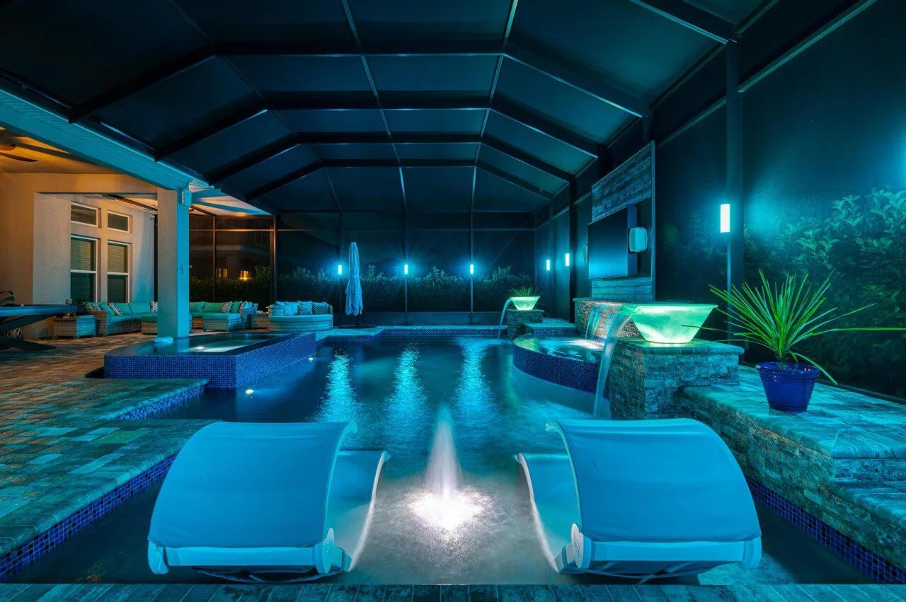 Teal LED pool cage lighting with cascading stone waterfalls